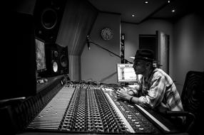 black and white photo of a young man in front of the keyboard in a music studio