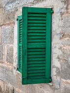 Close-up of the green window shutter in the stone wall of the building