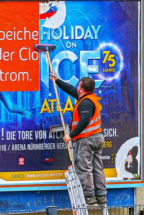Worker sticking colorful poster with the tool