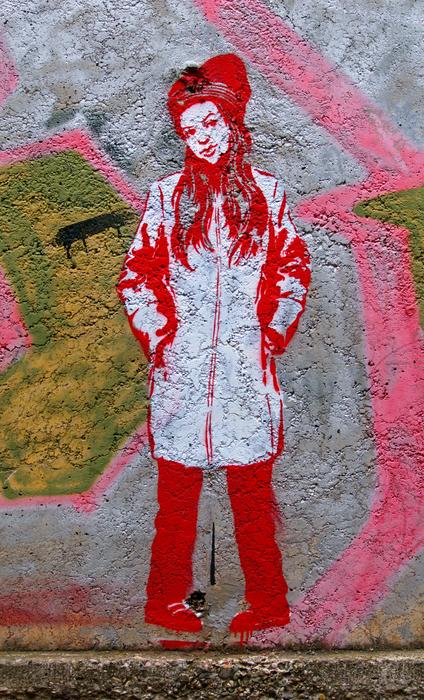 Red and white graffiti of the girl with hat, on the wall of the building
