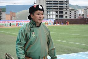 Man in national costume and hat, on the landscape with buildings and mountains