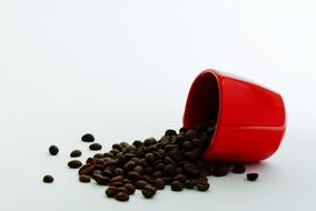 scattered coffee beans from a red mug