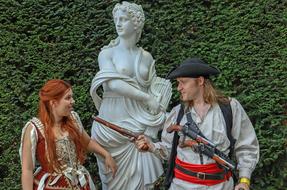 a girl and a guy in a pirate costume on the background of a statue