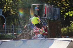 People at the skate park with colorful graffities, in sunlight, among the plants