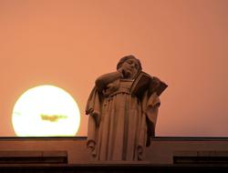 Statue of a wise man against the backdrop of a pink sunset