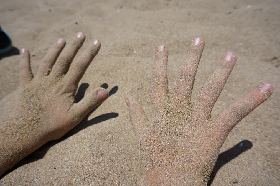 girls hands in the sand on the beach