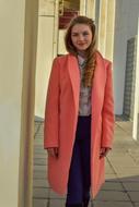 Portrait of the girl in pink coat, among the buildings