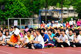 Students sitting on the track, in the school, among the green plants