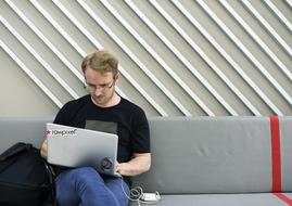 guy with laptop on gray sofa