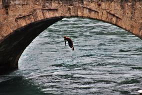 young man jumping from a stone bridge in Switzerland