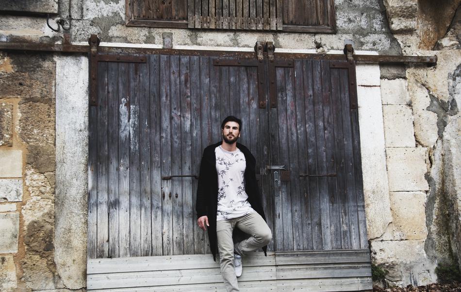 young man posing near wooden gate