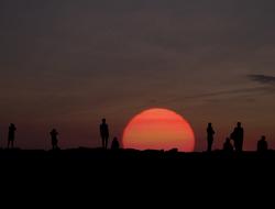 Landscape with the silhouettes of the people, at colorful and beautiful sunrise on horizon