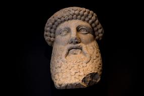 Statue of the head of the man with beard, at black background, in Rome, Italy