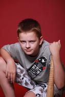 Portrait of the boy teen with the wooden stick, at red background