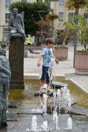 little boy cools down in a fountain