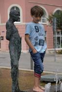 Child boy posing near the statue and building on the landscape