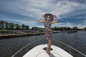 a girl in a dress and hat on a yacht