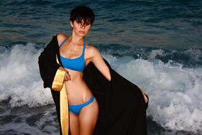 a girl in a blue swimsuit on the background of the sea