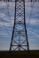 Electricity tower with cables, on the field, under the colorful sky with clouds