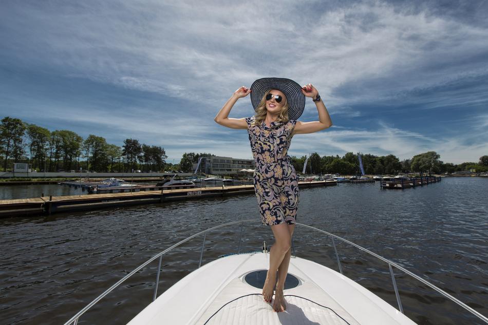 a girl in a dress and hat on a yacht