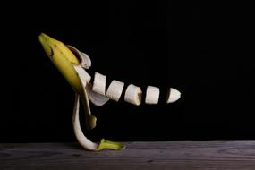 sliced banana in the air on a black background