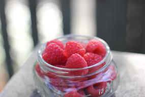 Juicy raspberries in a glass jar