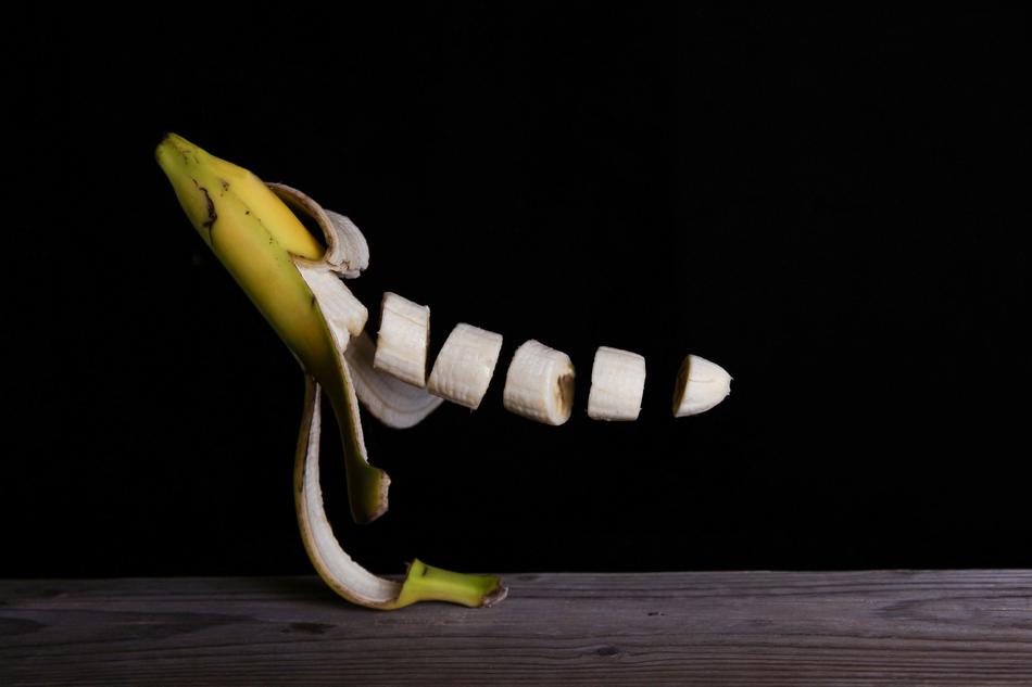 sliced banana in the air on a black background
