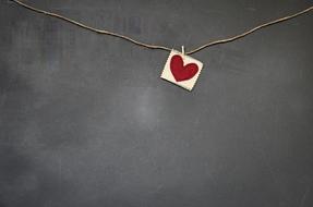 a card with a red heart on a string