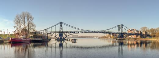 a long bridge by the lake with boats