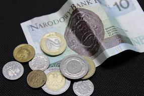 Close-up of the colorful Polish banknote and different coins, on the dark surface