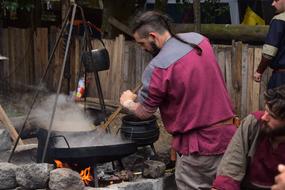 man cooks a meal over a campfire