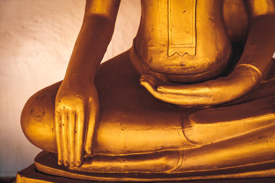 a golden sculpture of a buddha sitting