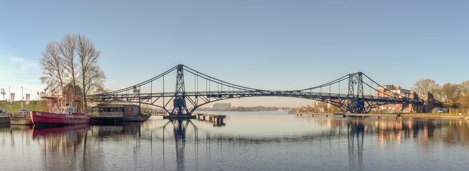 a long bridge by the lake with boats