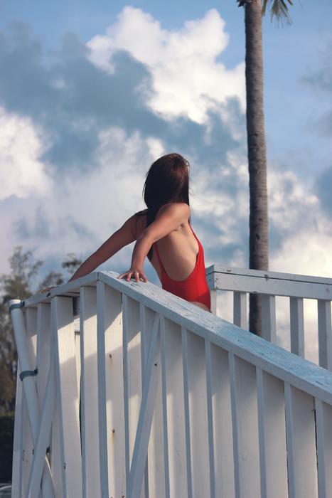 a girl in a red dress stands at the white railing