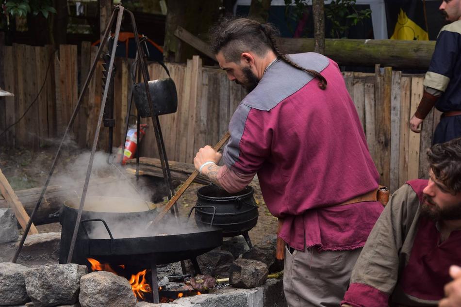man cooks a meal over a campfire