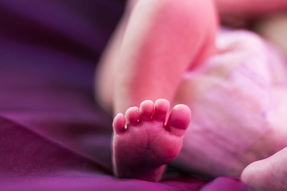 newborn's foot on a purple blanket