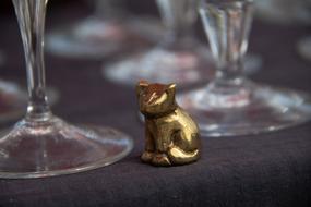 gold figurine of a cat on the background of glasses