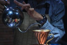 human pours water into a mug