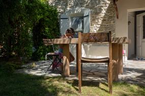 a child sits at a garden table in the shade