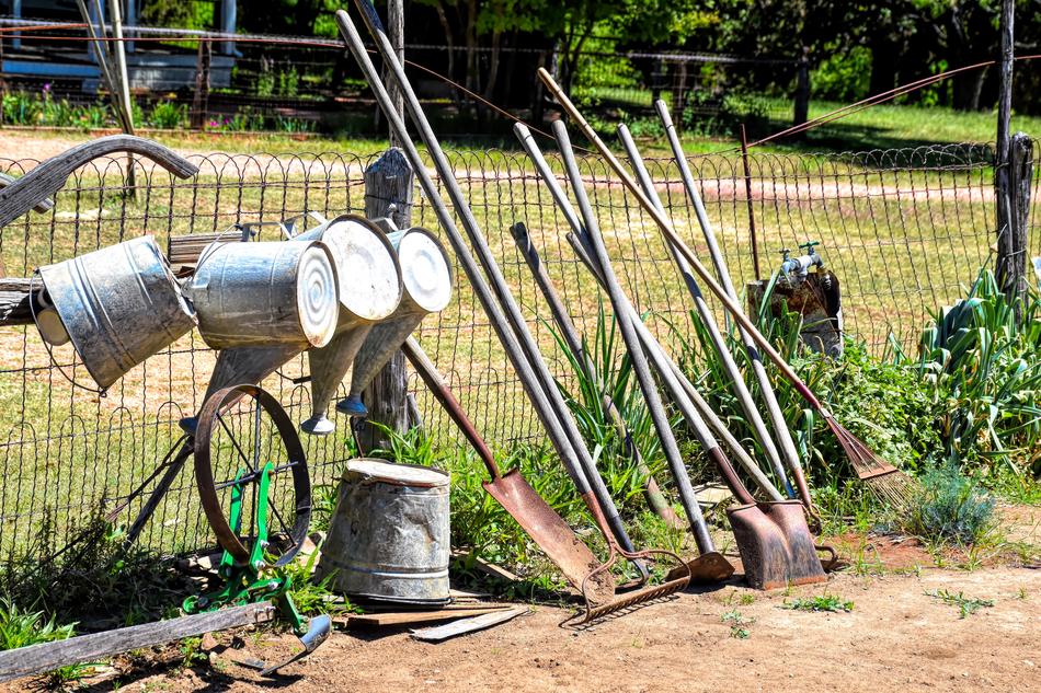 Garden tools near the fence and colorful plants on the landscape