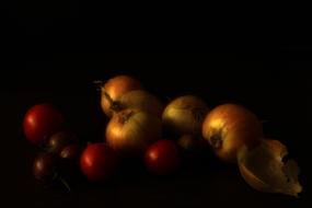 ripe tomatoes and onions on a black background