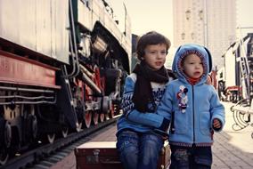 children sit on a suitcase on the platform of the Riga station in Moscow