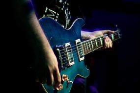 man plays blue rock guitar