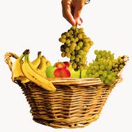 hand holding grapes over a fruit basket