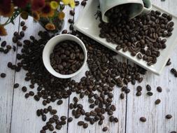 scattered coffee beans in the mug and on the table