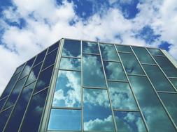reflection of white clouds in the facade of an office building