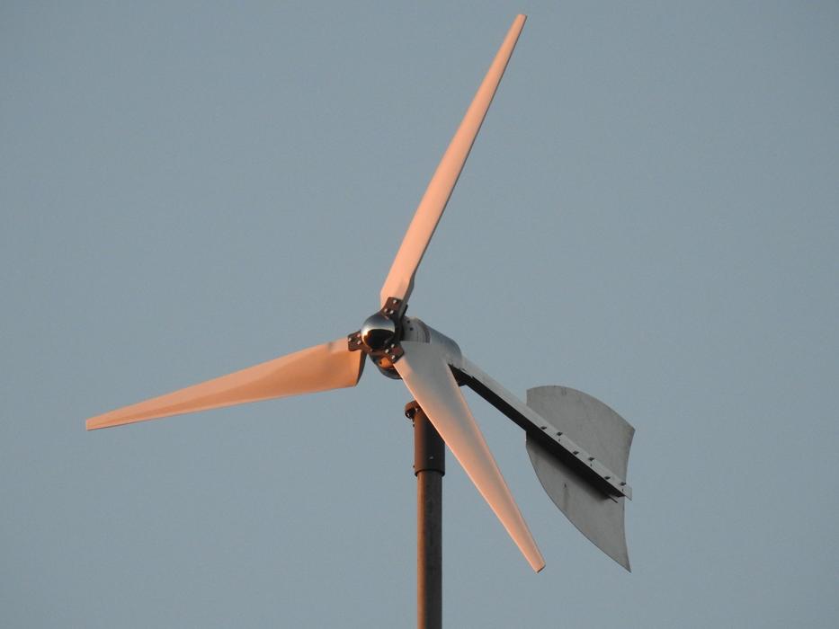 Close-up of the orange and grey wind turbine, at background with the sky