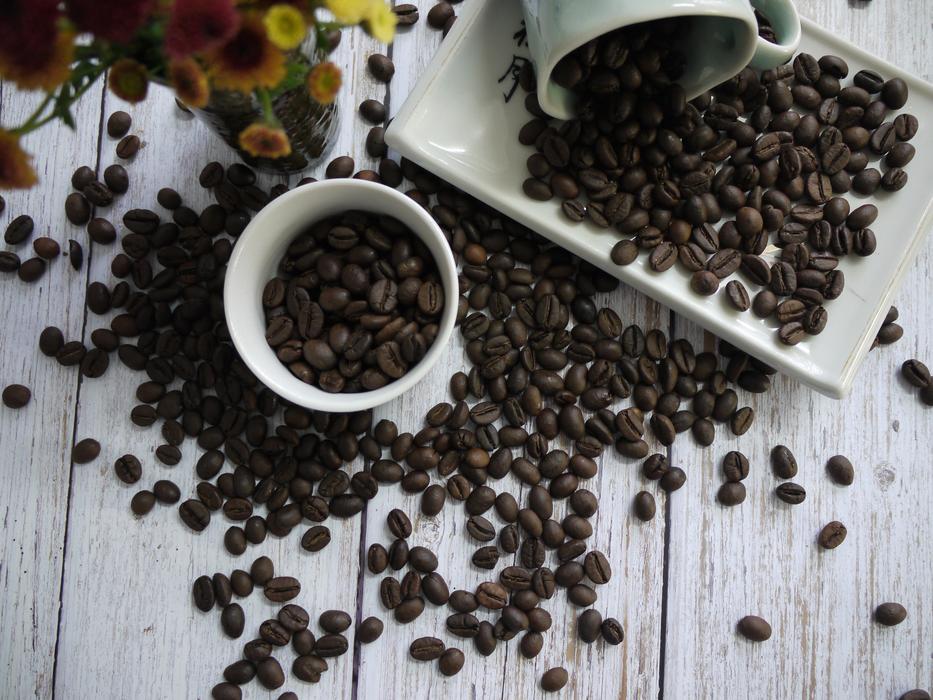 scattered coffee beans in the mug and on the table