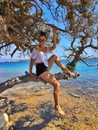 girl in a tree by the sea on the beach