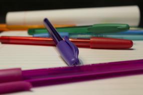 multicolored pens lie on an open notebook